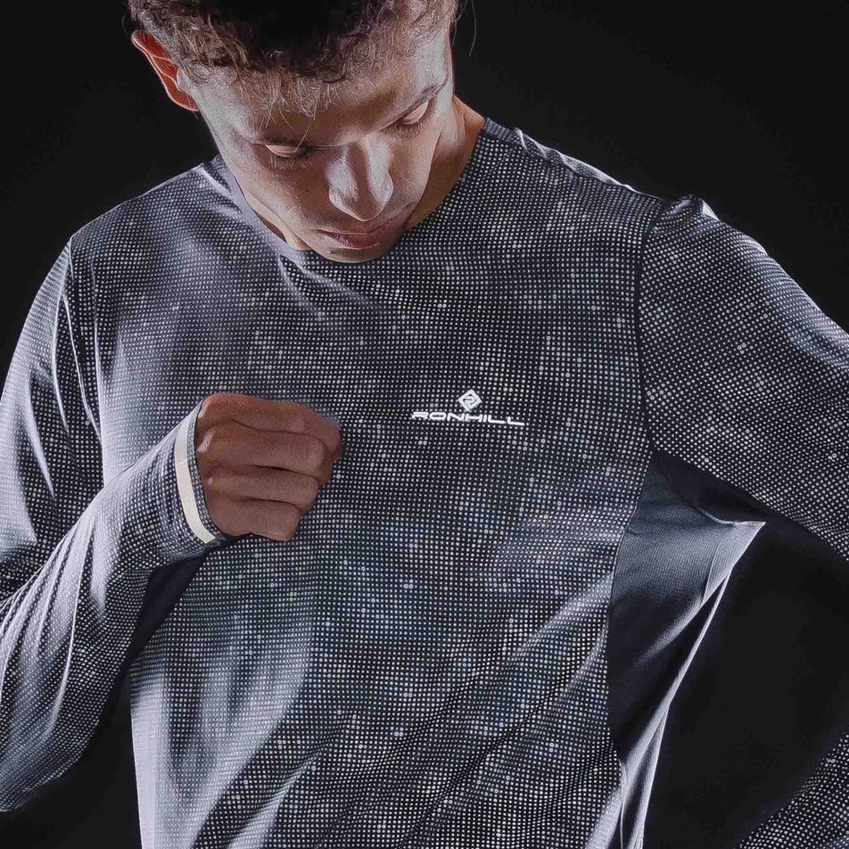 Front view of a model wearing the Ronhill Men's Tech Reflect Lux L/S Tee in the Black/Reflect colourway.