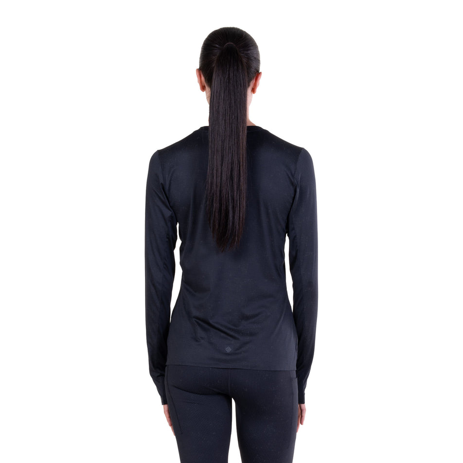 Back view of a model wearing the Ronhill Women's Tech Reflect Lux L/S Tee in the Black/Reflect colourway.