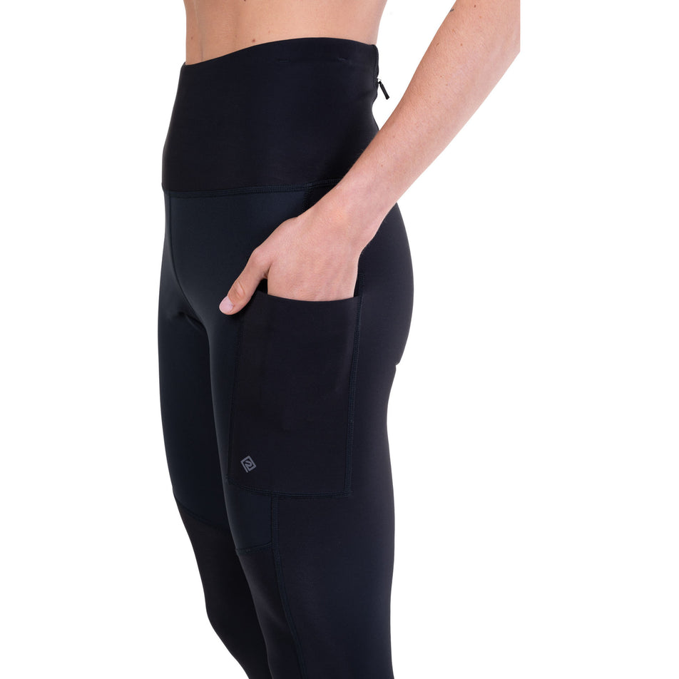 A model demonstrating the stash pocket on the Ronhill Women's Tech Wind-Block Tight in the All Black colourway.