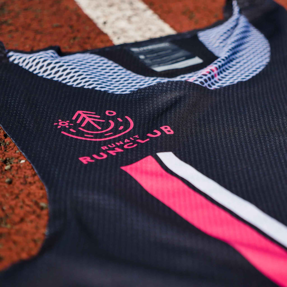 Close-up of the Pressio logo and Run4It Run Club logo on the front of the Pressio Run4It Run Club Men's Elite Singlet. (8489124266146)