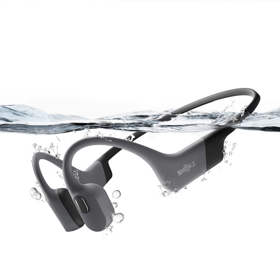 A pair of Shokz Unisex OpenSwim Pro Wireless Bone Conduction Headphones in the Grey colourway, partially submerged under water.  (8493802913954)