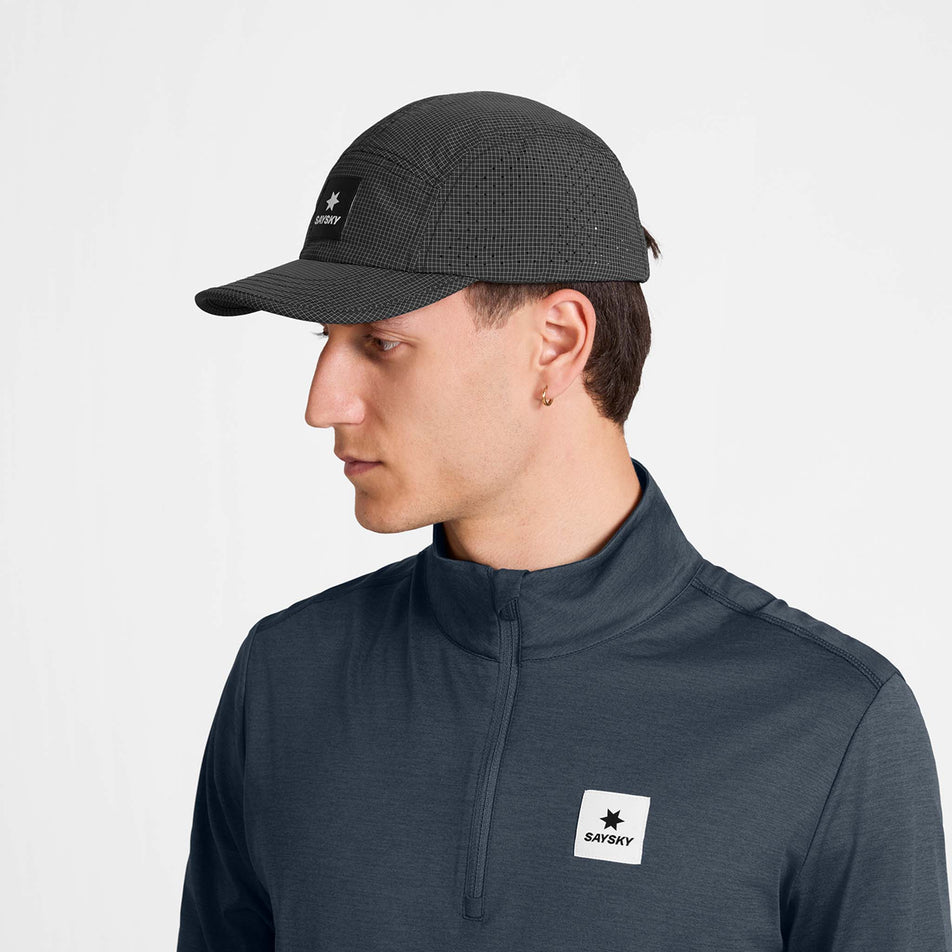 Front view of a model wearing the SAYSKY Unisex Combat Shield Cap in the Black colourway.