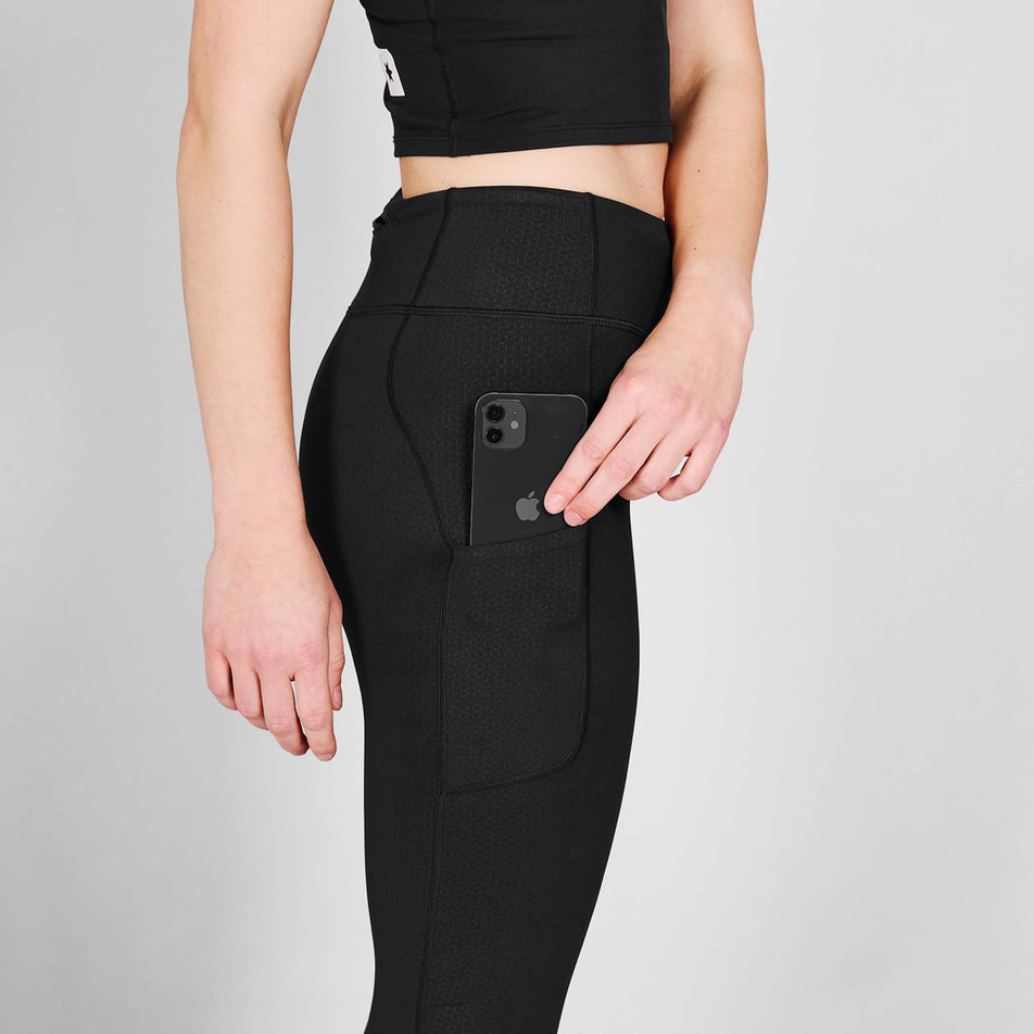 A model demonstrating the drop-in pocket on the side of the SAYSKY Women's Pace+ Long Tights in the Black colourway.