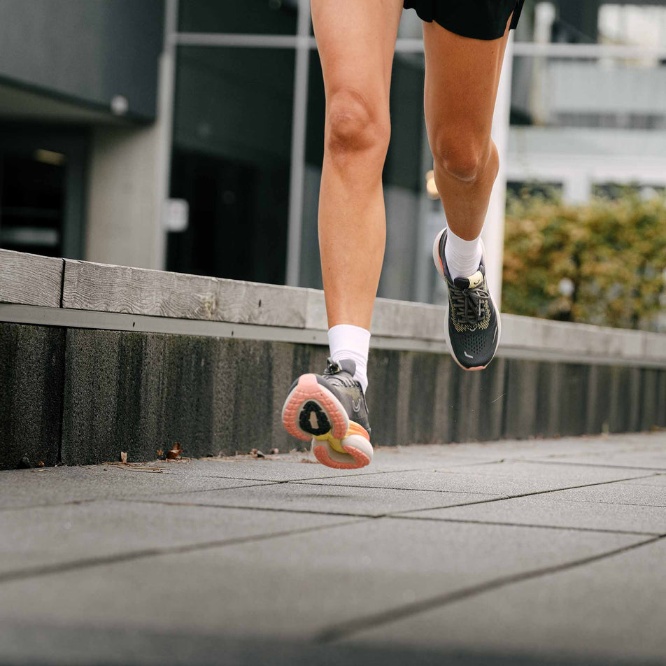 A model running in a pair of True Motion Women's U-Tech Nevos 3 Running Shoes in the Asphalt/Antarctica/Peach Amber colourway. (8636671459490)