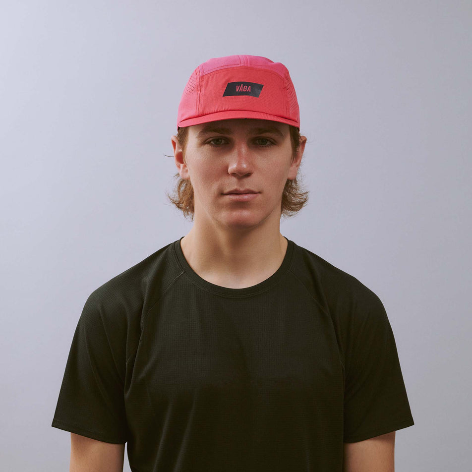 Front view of a model wearing the VÅGA Unisex Feather Racing Cap in the Pink colourway.