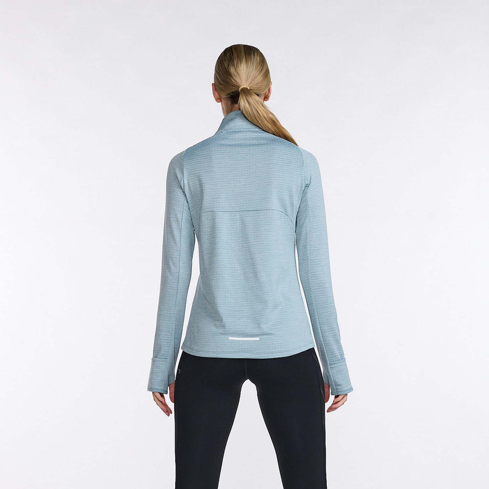 Back view of a model wearing a 2XU Women's Ignition 1/4 Zip top in the Chambray/White Reflective colourway. Model is also wearing leggings. (8108368953506)