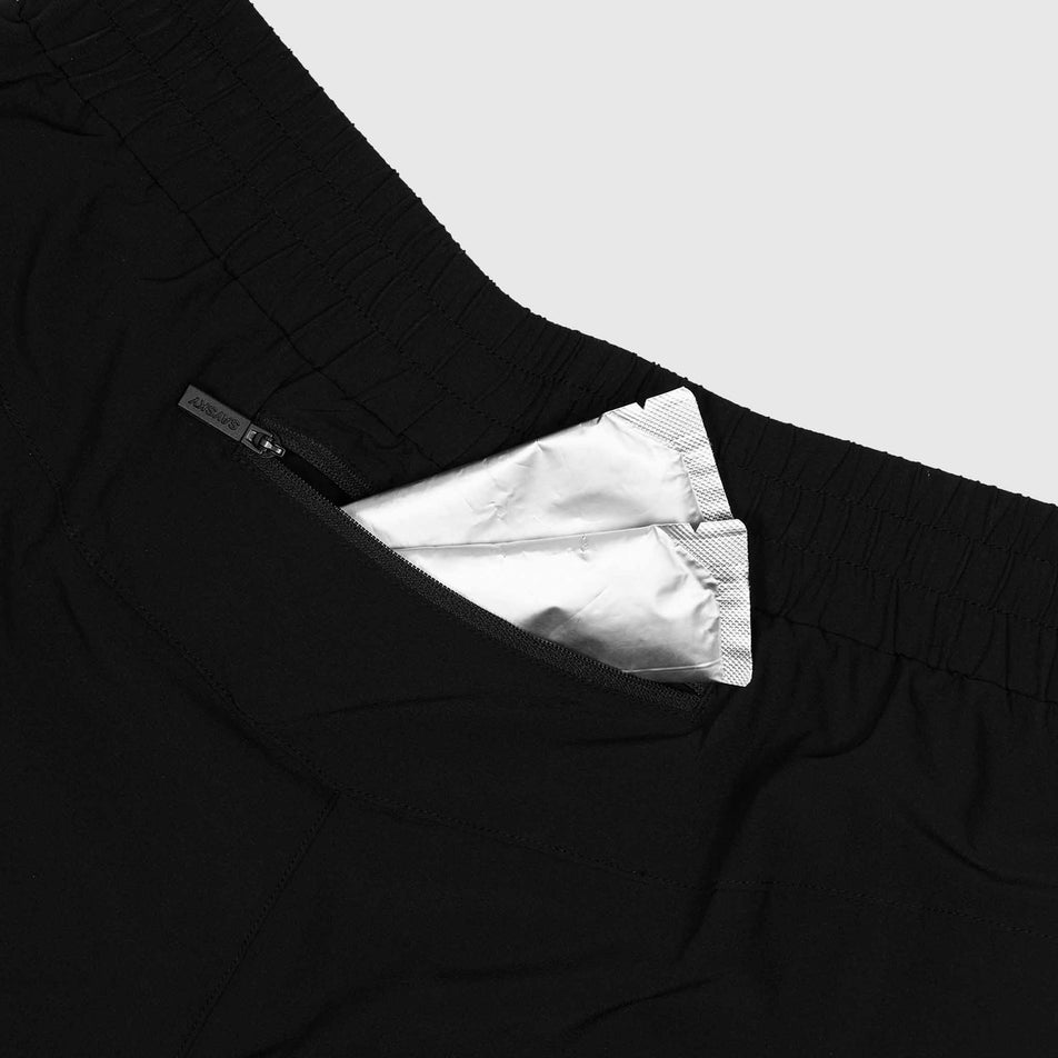 Energy gels sticking out the zipped back pocket of the SAYSKY Unisex Pace Pants in the Black colourway. (8602035814562)
