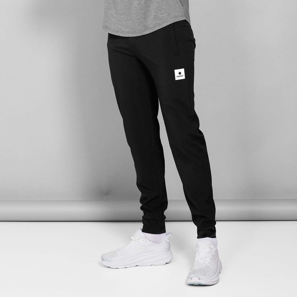Front view of a model wearing the SAYSKY Unisex Pace Pants in the Black colourway. Model is also wearing a top, socks and shoes. (8602035814562)