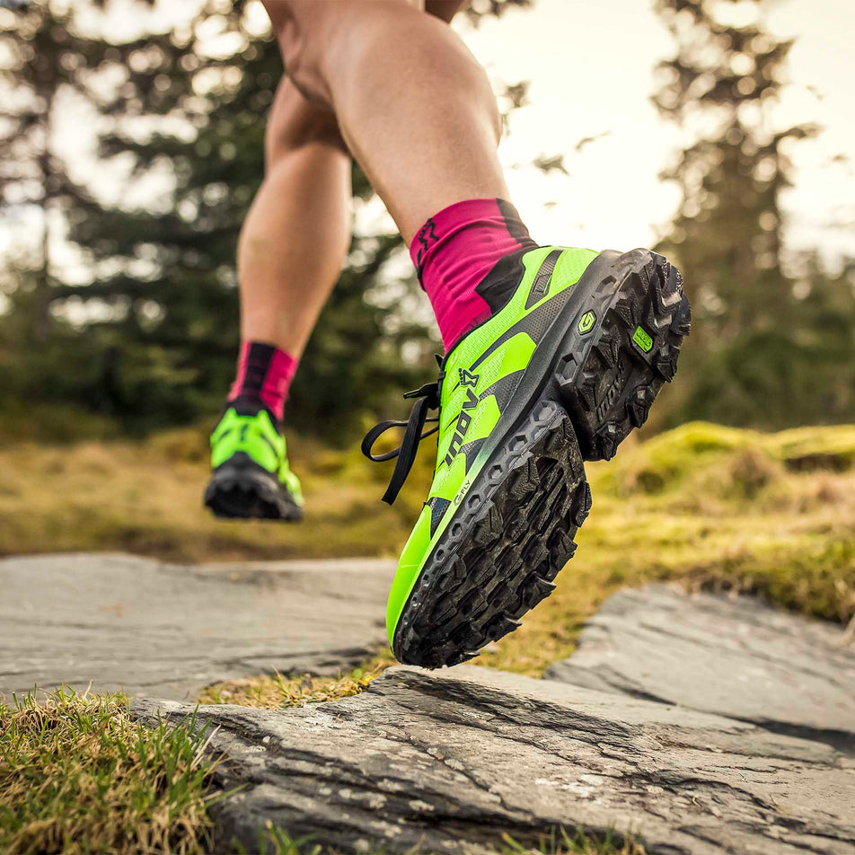 A model wearing a pair of Inov-8 TrailFly Ultra G 300 Max whilst running on wet rock (6897229627554)