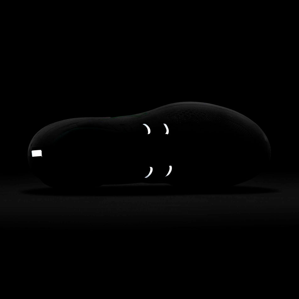 Reflective heel tab and midfoot bands on the left shoe from a pair of women's Nike React Miler 2 glowing in a dark surrounding (6899776454818)