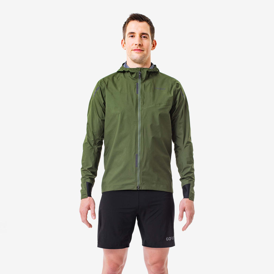 Front view of a model wearing a GOREWEAR Men's Concurve GORE-TEX Jacket in the Utility Green colourway. Model is also wearing GOREWEAR shorts. (8166448300194)