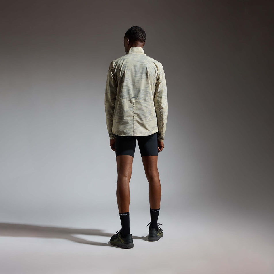 Back view of a model wearing the GOREWEAR Men's Concurve Electro Windbreaker in the Crushed Tech Beige/Lab Gray colourway.