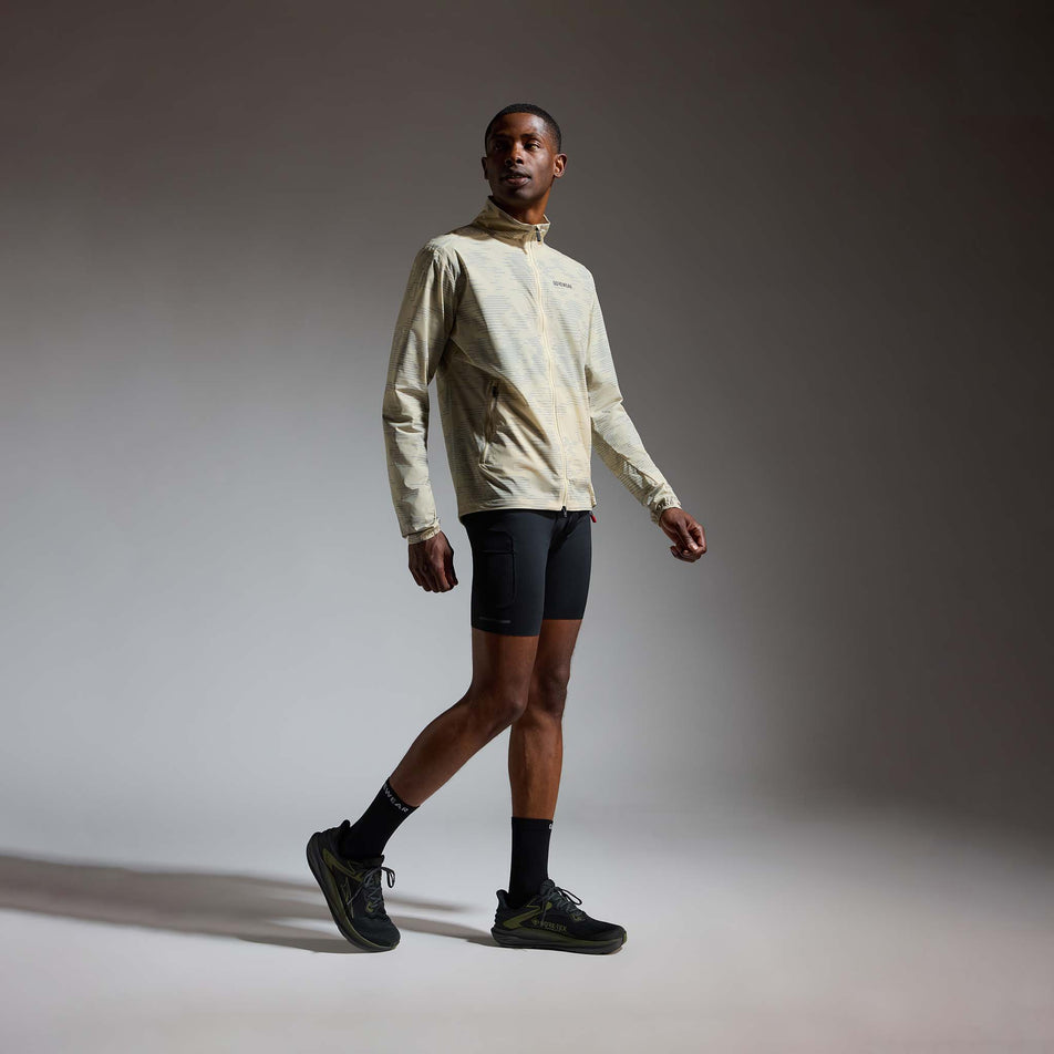 Angled view of a model wearing the GOREWEAR Men's Concurve Electro Windbreaker in the Crushed Tech Beige/Lab Gray colourway.