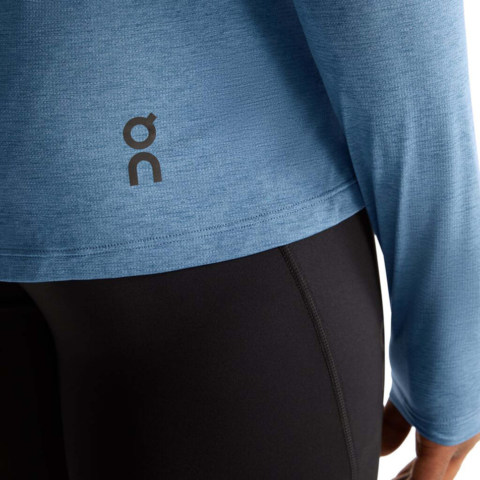 Close-up view of a model wearing an On Men's Performance Long-T in the Stellar colourway. Lower right section of the t-shirt is visible, with the On logo on display.  (8005042995362)