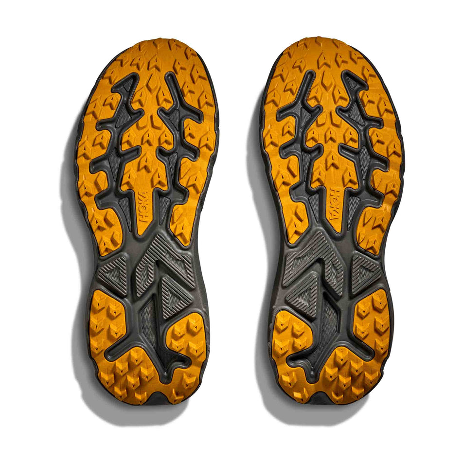 The outsoles of a pair of HOKA Men's Challenger 8 GTX Running Shoes in the Asphalt Grey/Varsity Yellow colourway.
