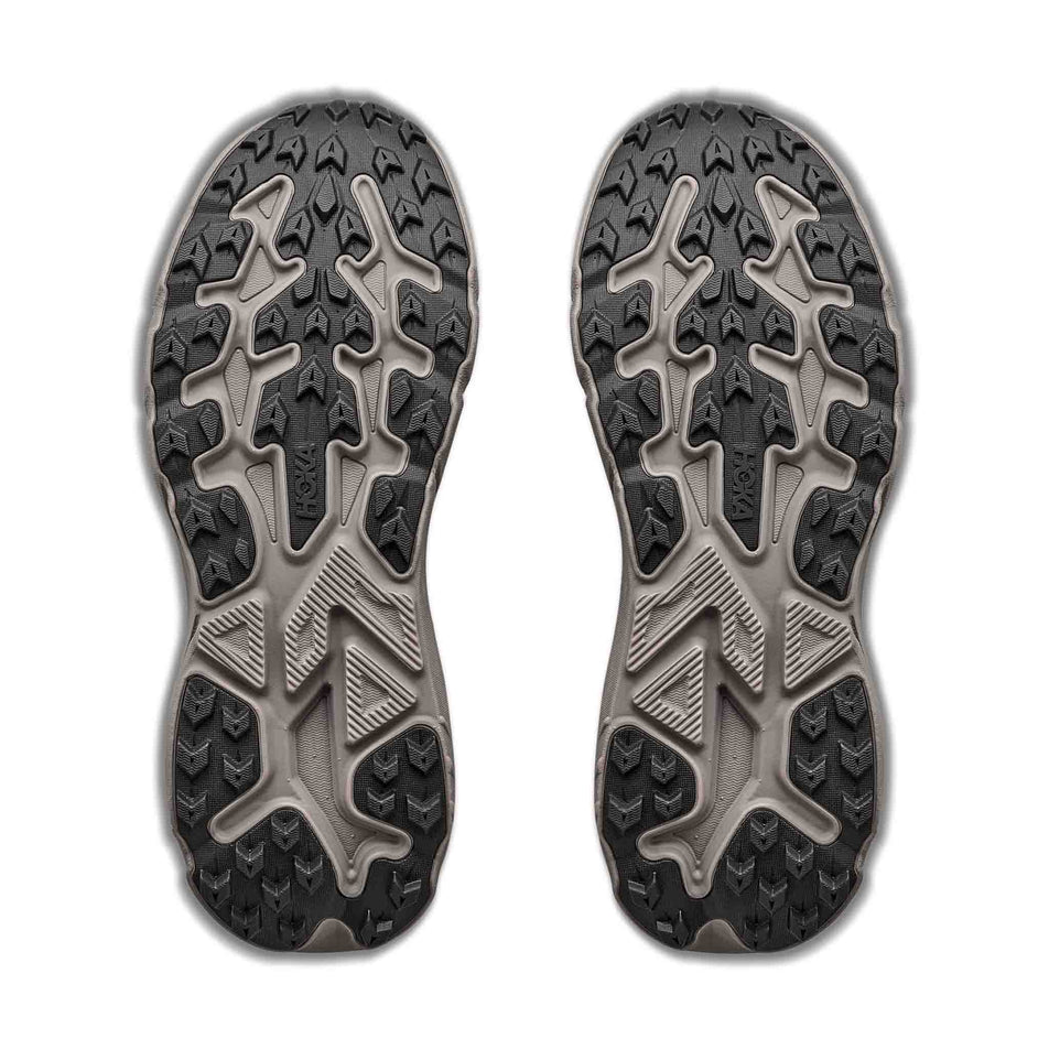 The outsoles of a pair of HOKA Men's Challenger 8 GTX Trail Running Shoes in the Pebble Grey/Boulder Grey colourway.