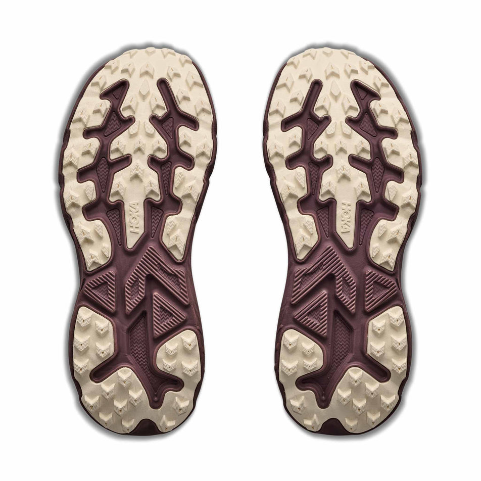 The outsoles of a pair of HOKA Women's Challenger 8 GTX Trail Running Shoes in the Smoky Quartz/Alabaster colourway.