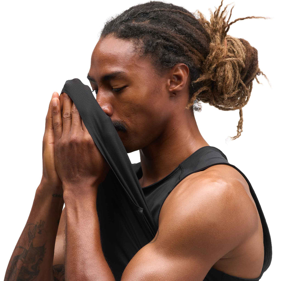 Angled view of a model wearing the HOKA Men's Everyrun Tank in the Black colourway.