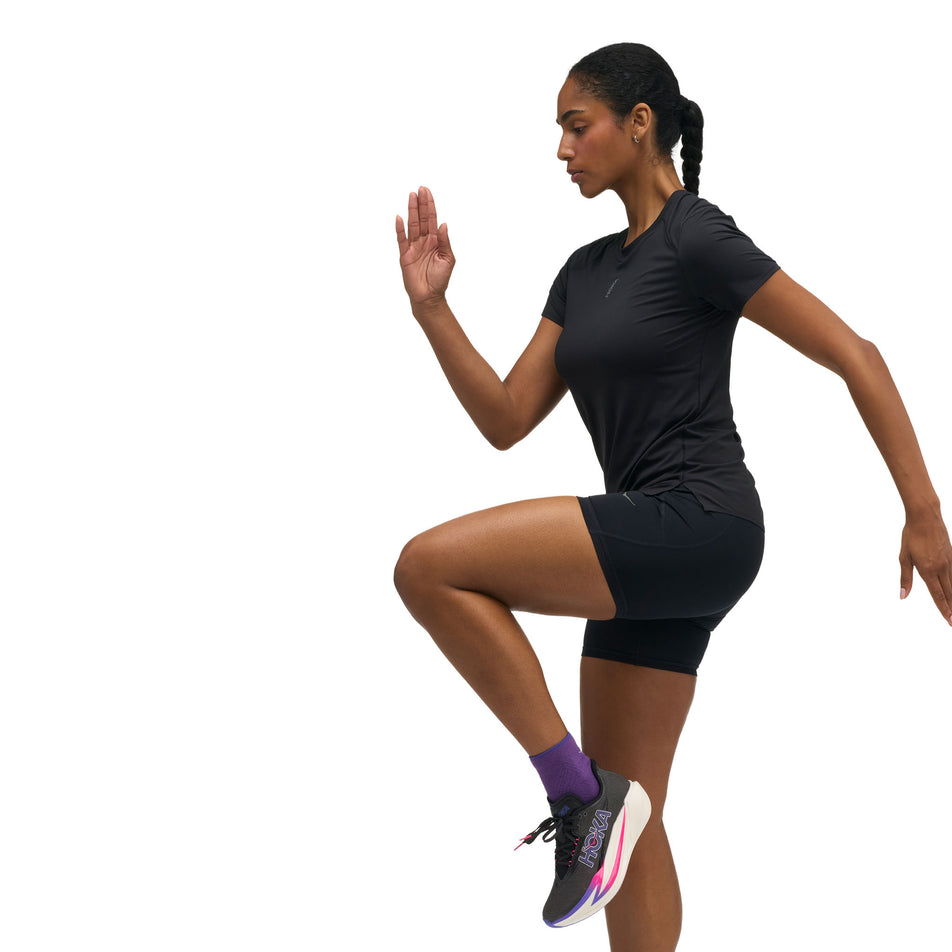 Angled view of a model wearing the HOKA Women's Everyrun Short Sleeve in the Black colourway.