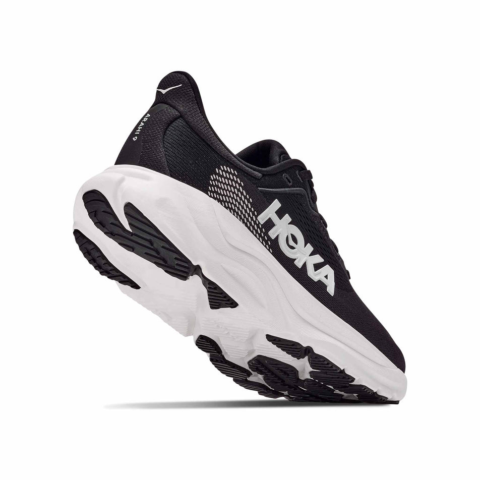 Lateral - and outsole - view of the right shoe from a pair of HOKA Men's Arahi 9 Wide Running Shoes in the Black/White colourway.