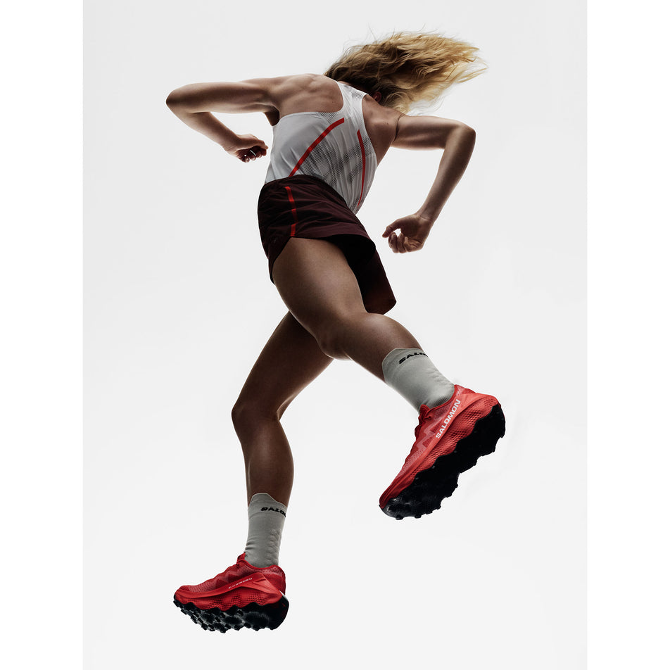 A model wearing a pair of Salomon Unisex S/Lab Ultra Glide 1.5 Running Shoes in the Fiery Red/Fiery Red colourway.