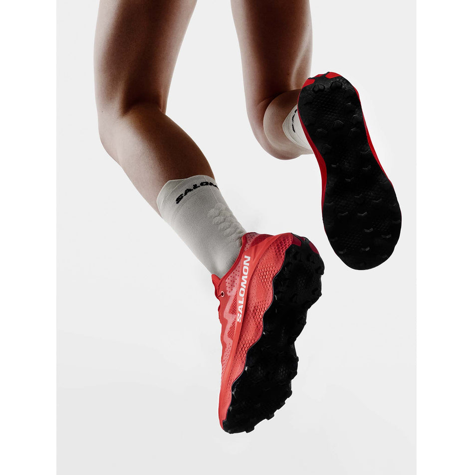 A model wearing a pair of Salomon Unisex S/Lab Ultra Glide 1.5 Running Shoes in the Fiery Red/Fiery Red colourway.