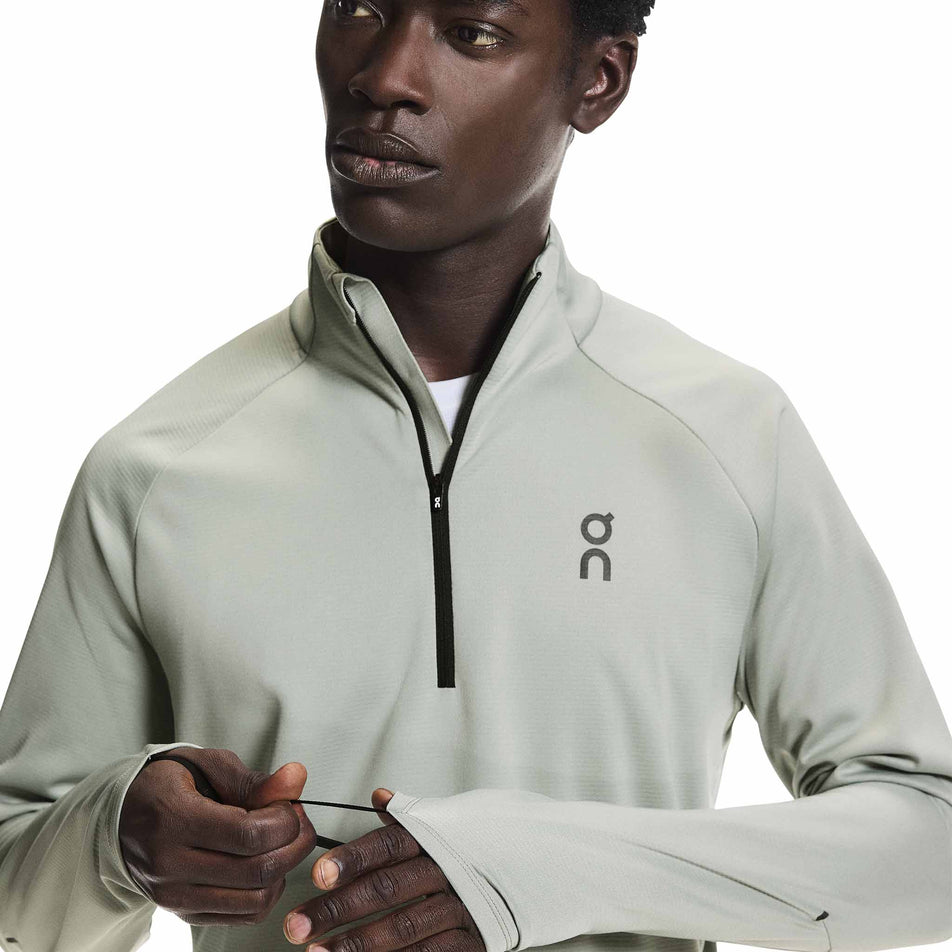 A model demonstrating the thumbloops on the On Men's Climate Shirt in the Tin colourway.