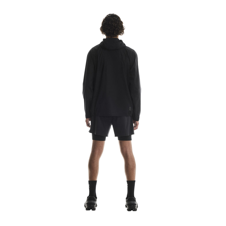 Back view of a model wearing the On Men's Performance Waterproof Jacket in the Black colourway. (8790101819554)