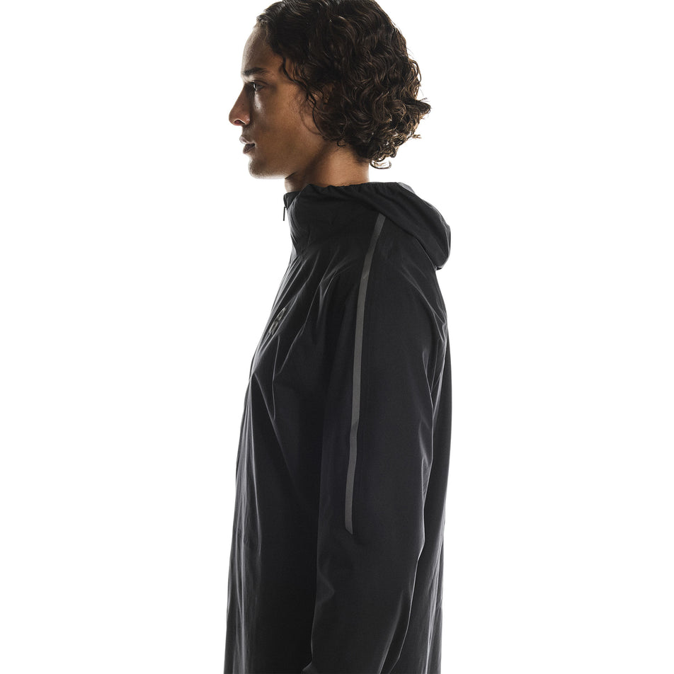 Side view of a model wearing the On Men's Performance Waterproof Jacket in the Black colourway. (8790101819554)