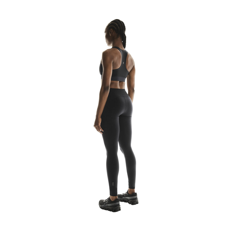 Angled view of a model wearing the On Women's Performance Tights in the Black colourway.