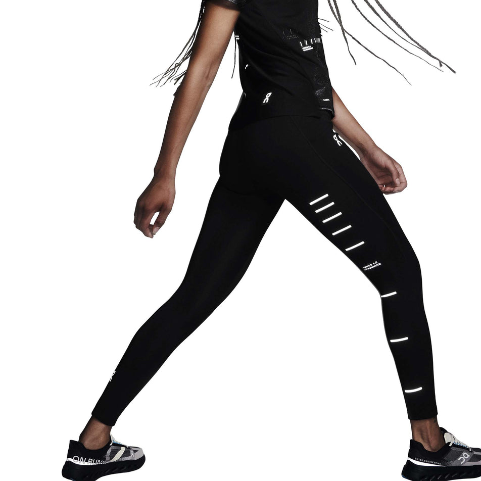 Side view of a model wearing the On Women's Performance Tights Lumos in the Black colourway. (8790043394210)