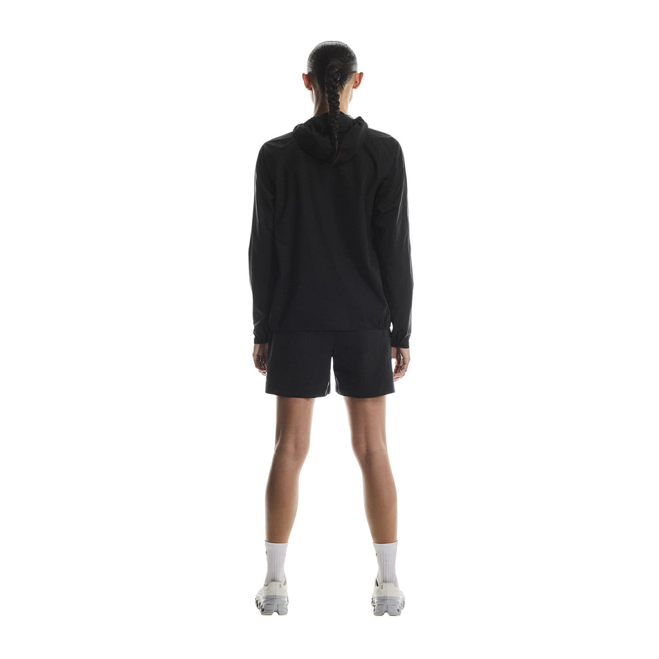 Back view of a model wearing the On Women's Performance Waterproof Jacket in the Black colourway. (8790002696354)