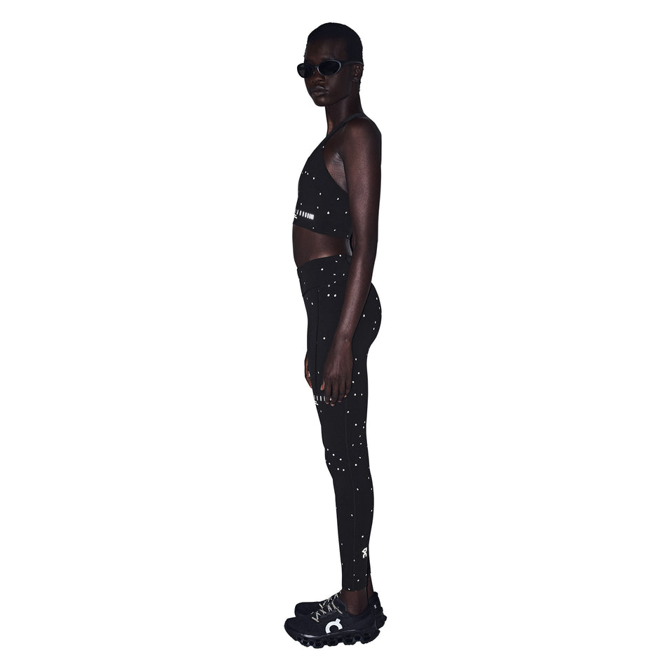 Side view of a model wearing the On Women's Performance Tights Lumos 2.0 in the Black/Eclipse colourway.