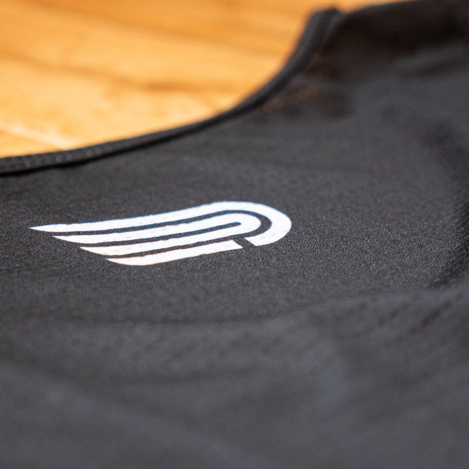 Close-up view of the Pressio logo on the EMF Official Licensed Merchandise | Pressio Men's Prevail Singlet in the Black/Stone colourway.
