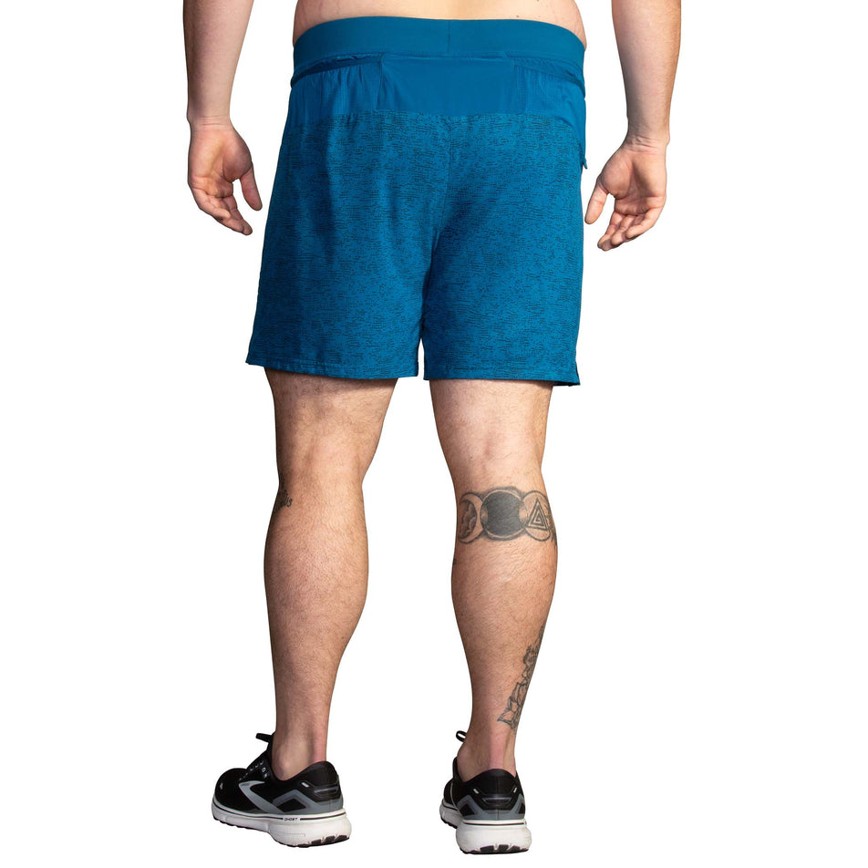 Back view of a model wearing a pair of Brooks Men's Sherpa 7 Inch 2-in-1 Shorts in the Dark Ocean Terrain Print colourway (8007477133474)