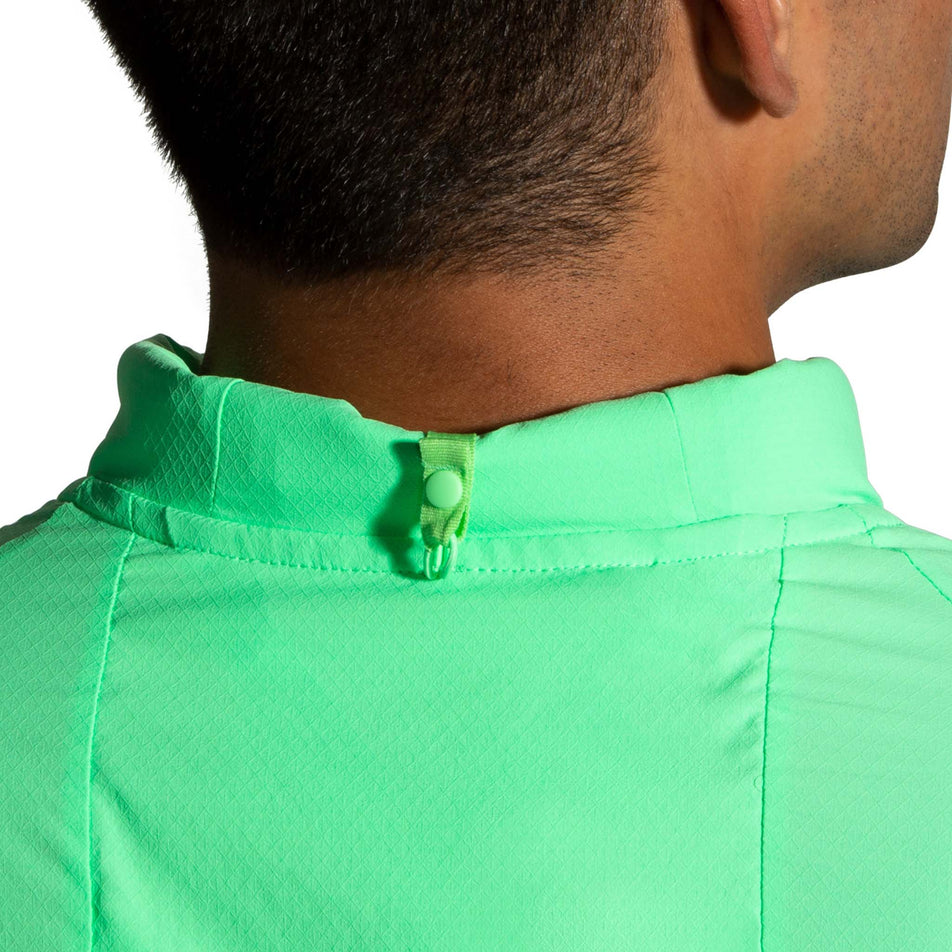 Close-up of a model wearing a Brooks Men's Canopy Jacket in Neo Green. Upper part of the back of the collar is visible.  (8007418314914)