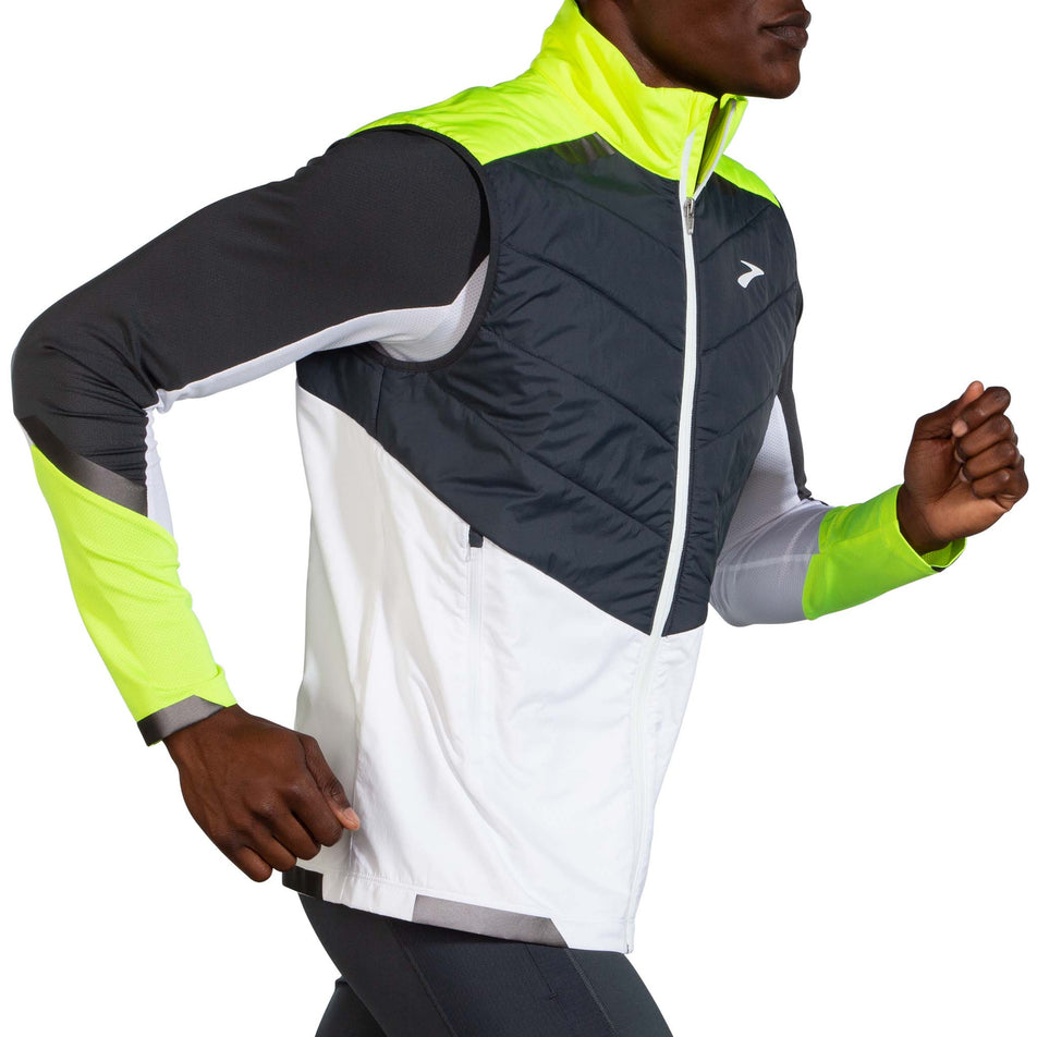 Side view of model wearing a Brooks Men's Run Visible Insulated Vest in the White/Asphalt/Nightlife colourway. Model is wearing also wearing a Brooks long sleeve top. (8059815329954)