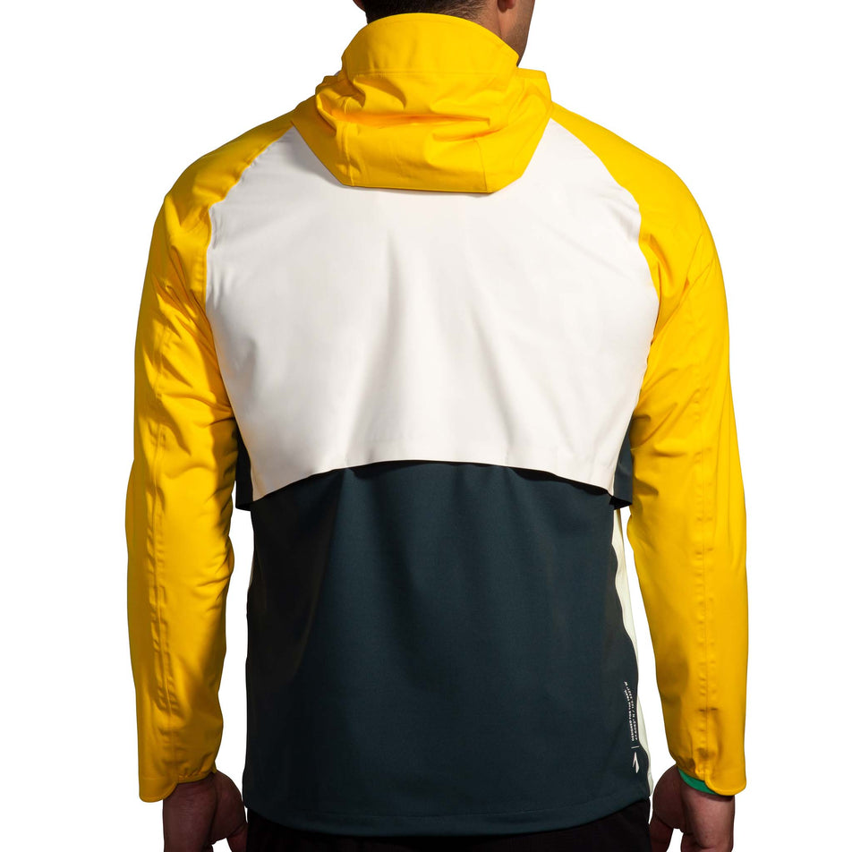 Back view of a model wearing a Brooks Men's High Point Waterproof Jacket in the Glacier Green/Ecru/Lemon colourway. Model is also wearing Brooks legwear. (8177405821090)