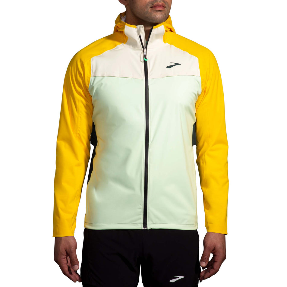 Front view of a model wearing a Brooks Men's High Point Waterproof Jacket in the Glacier Green/Ecru/Lemon colourway. Model is also wearing Brooks legwear. (8177405821090)