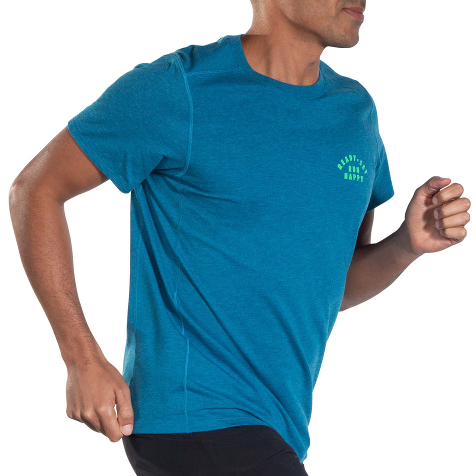 Angled front view of a model wearing a Brooks Men's Distance Short Sleeve 2.0 Running T-shirt in the Heather Dark Ocean/Ready Set Run Happy colourway. Model is in a running pose.  (8007464091810)