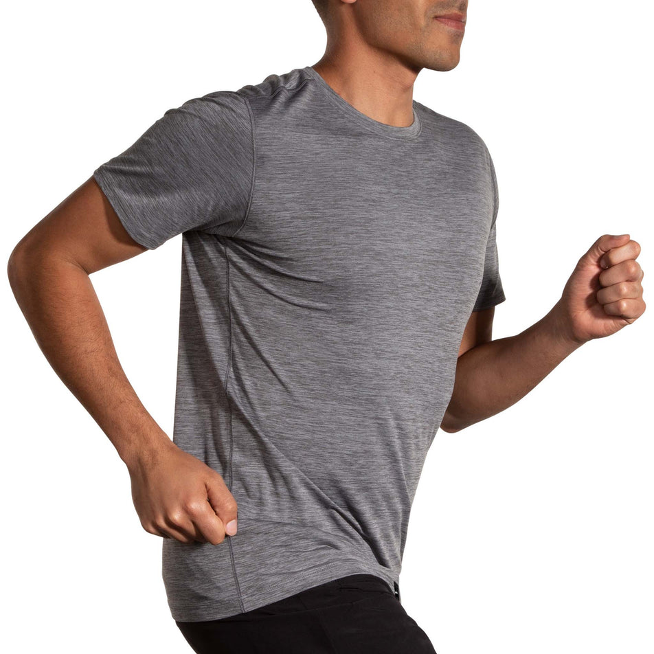 Angled front view of a model wearing a Brooks Men's Luxe Short Sleeve in the Heather Charcoal colourway. Model is also wearing Brooks legwear. (8177449074850)