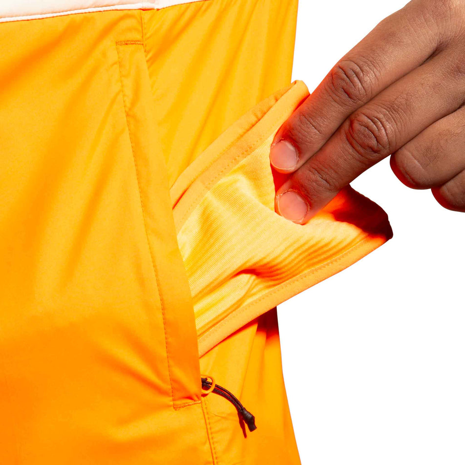 The side pocket on the Brooks Men's Run Visible Insulated Vest 2.0 in the Ecru/Fluoro Flash/Black colourway. (8778447224994)