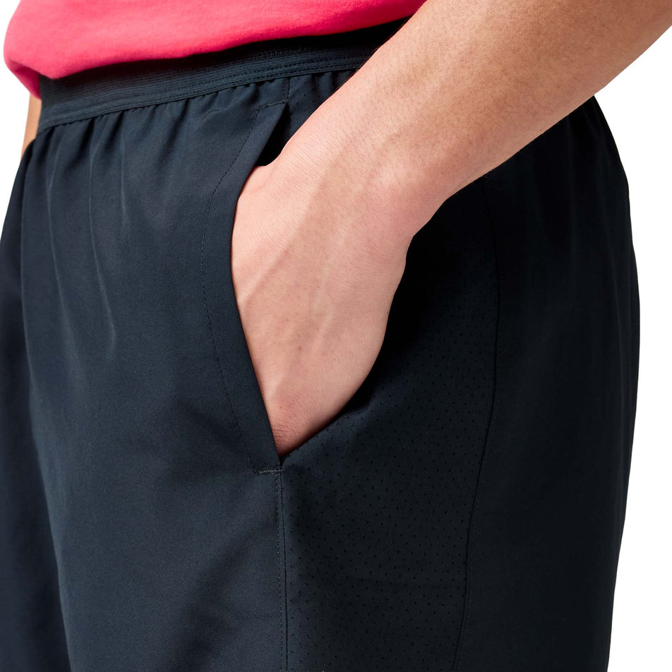 Side view of a model wearing the Brooks Men's Dash Shorts in the Black colourway.