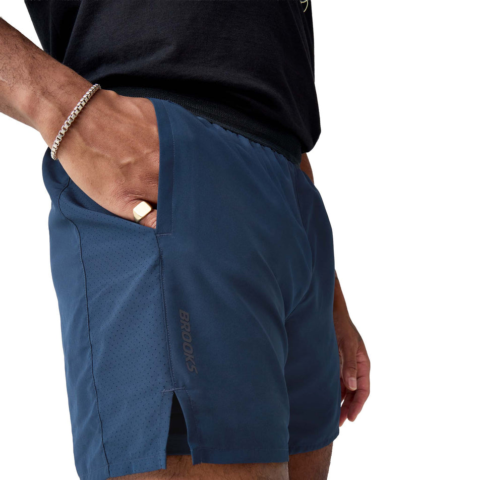Side view of a model wearing the Brooks Men's Dash 2-in-1 Short in the Midnight Run/Black colourway.