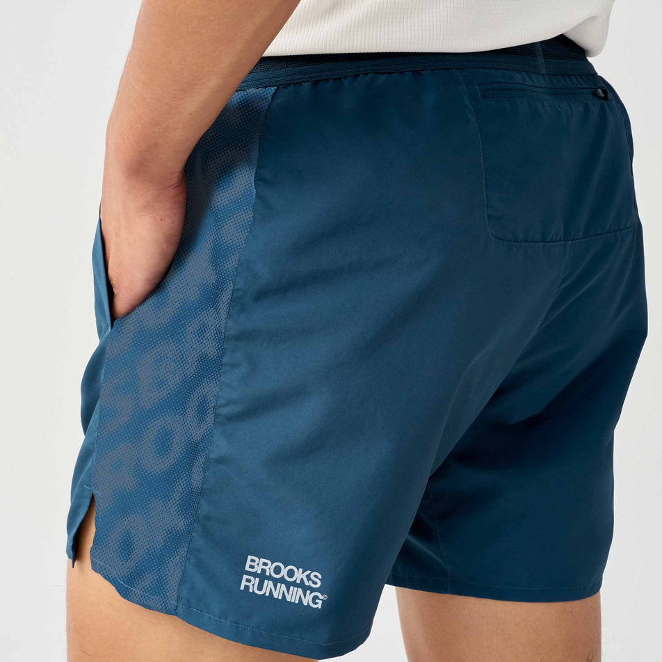 Angled view of a model wearing the Brooks Men's Dash Reflective Short in the Reflective Wordmark Indigo colourway.