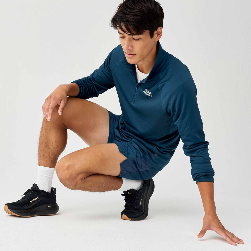Angled view of a model wearing the Brooks Men's Dash Reflective Short in the Reflective Wordmark Indigo colourway.