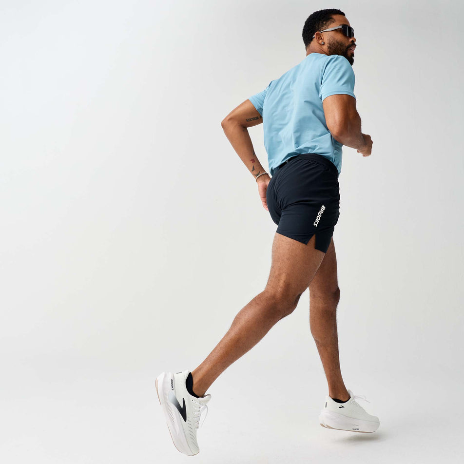 Angled view of a model wearing the Brooks Men's Dash Cooling Short in the Black colourway.