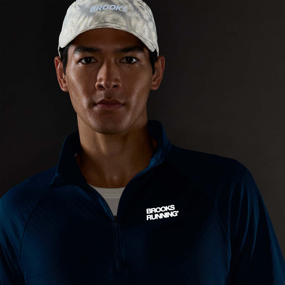 The reflective graphic on the front of the Brooks Men's Thermal Reflective 1/2 Zip in the Reflective Wordmark Indigo colourway.