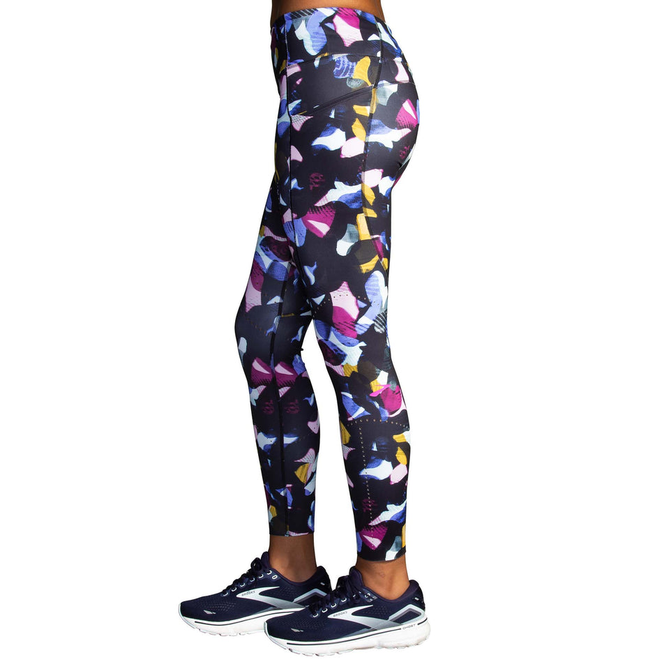 Left-lateral view of a model wearing a pair of Brooks Women's 7/8 Tights in the Fast Floral Print colourway (8007499481250)