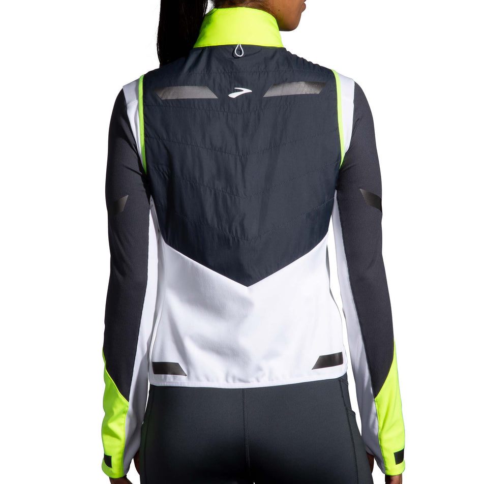 Back view of a model wearing a Women's Run Visible Insulated Vest in the White/Asphalt/Nightlife colourway. Model is also wearing a Brooks long sleeve top. (8059825914018)
